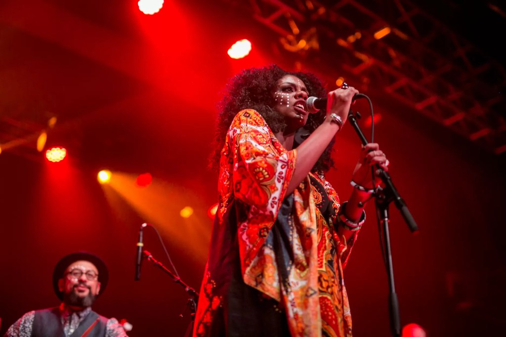 An African-American woman in a red dress sings into a microphone.
