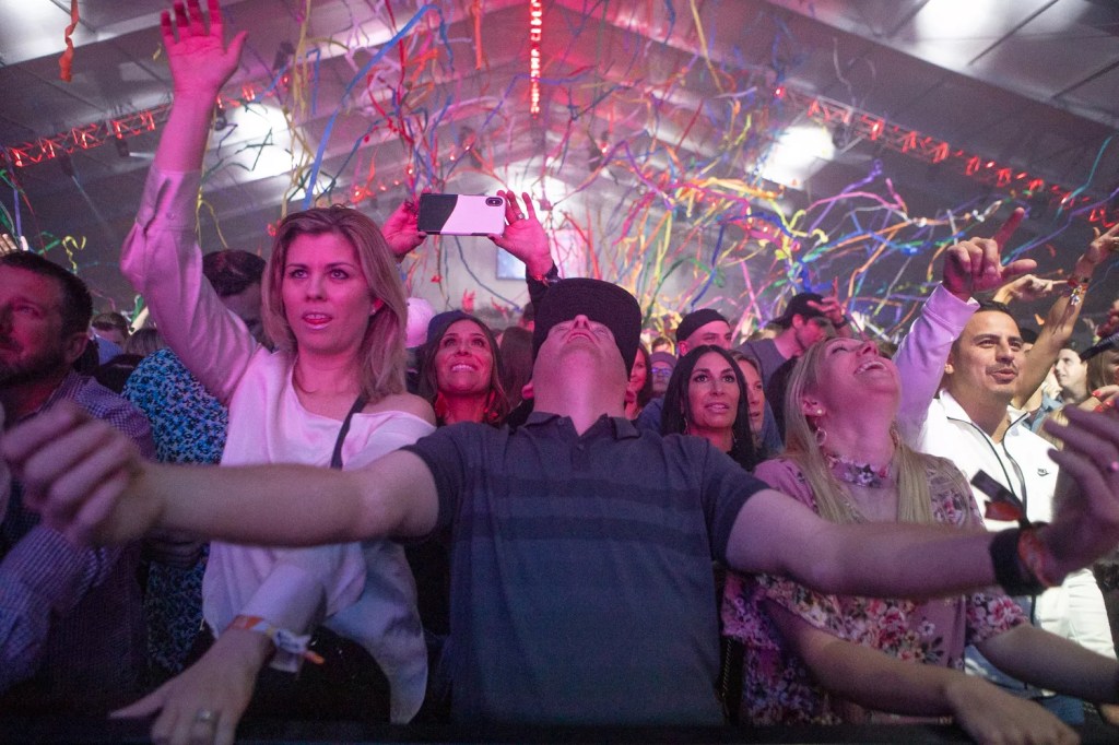 Fans throw their arms in the air as confetti rains down during a packed concert inside the Coors Light Birds Nest.