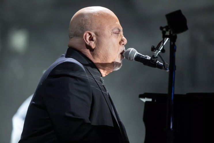 Rock 'n' roll legend Billy Joel singing into a microphone.