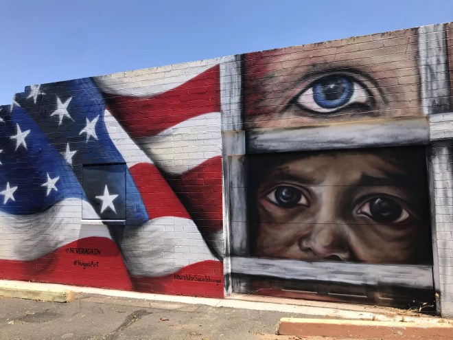 a mural with an american flag and faces looking out from behind bars