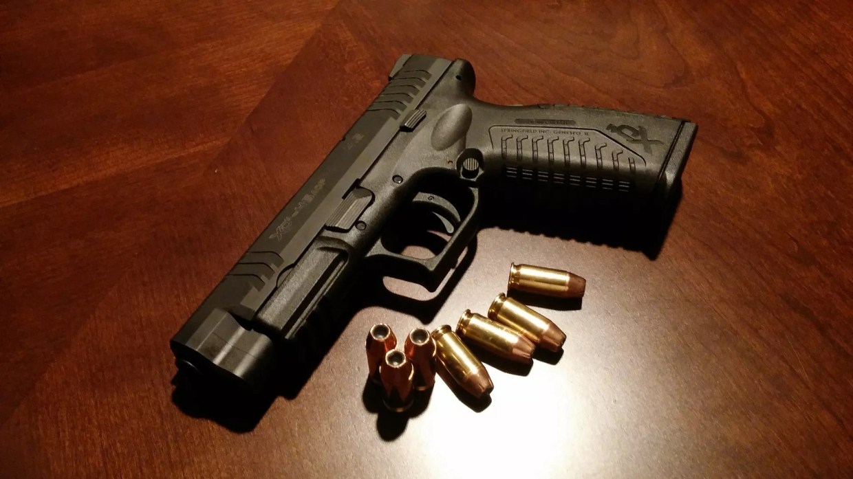 A handgun with bullets laid out around it.