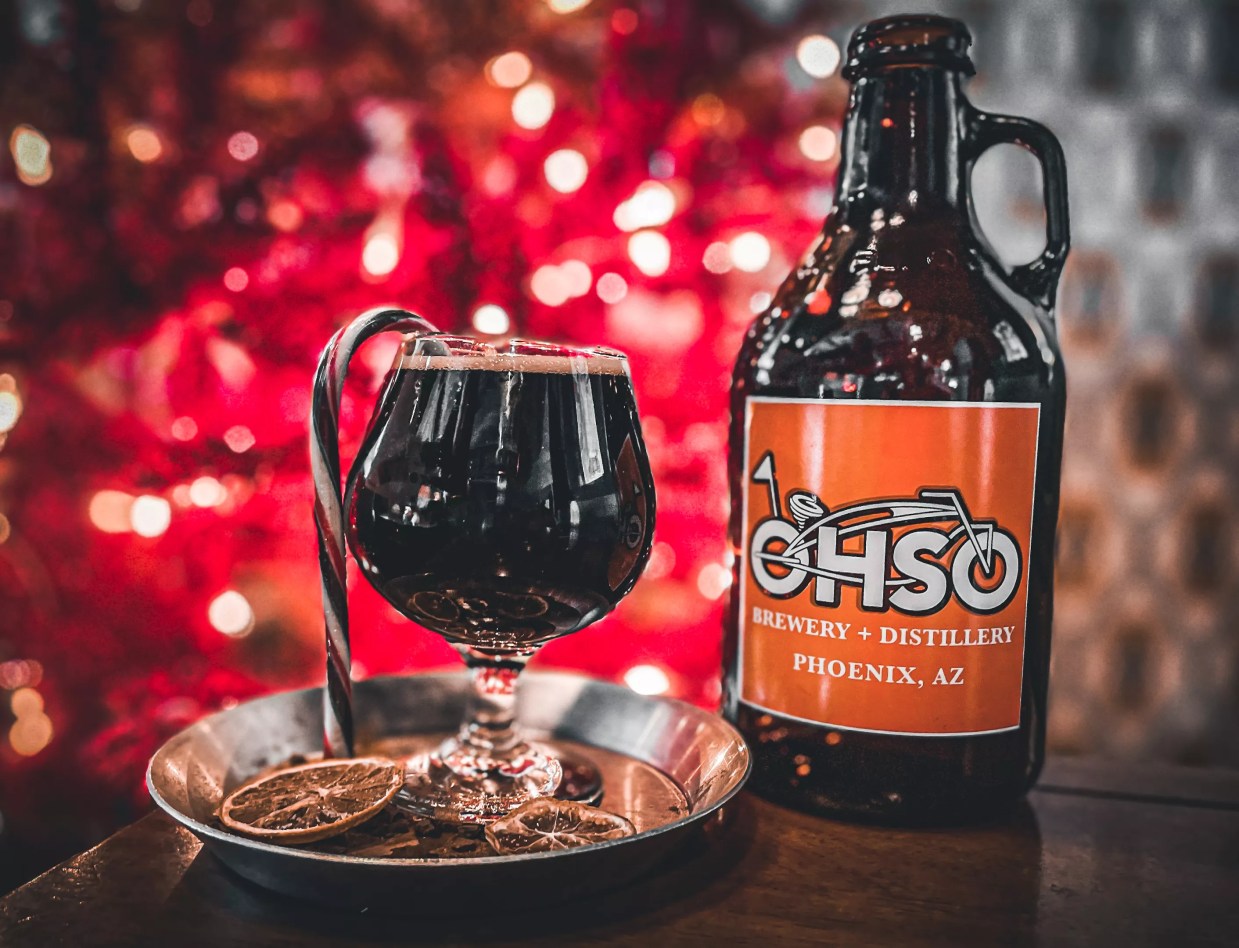 A pint of O.H.S.O. seasonal beer in front of a Christmas tree.