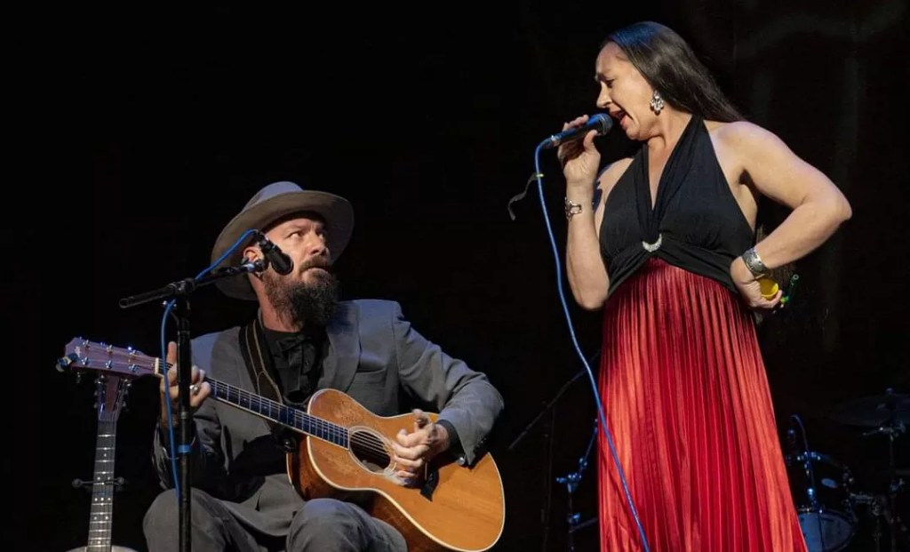 A male guitarist and female singer perform.