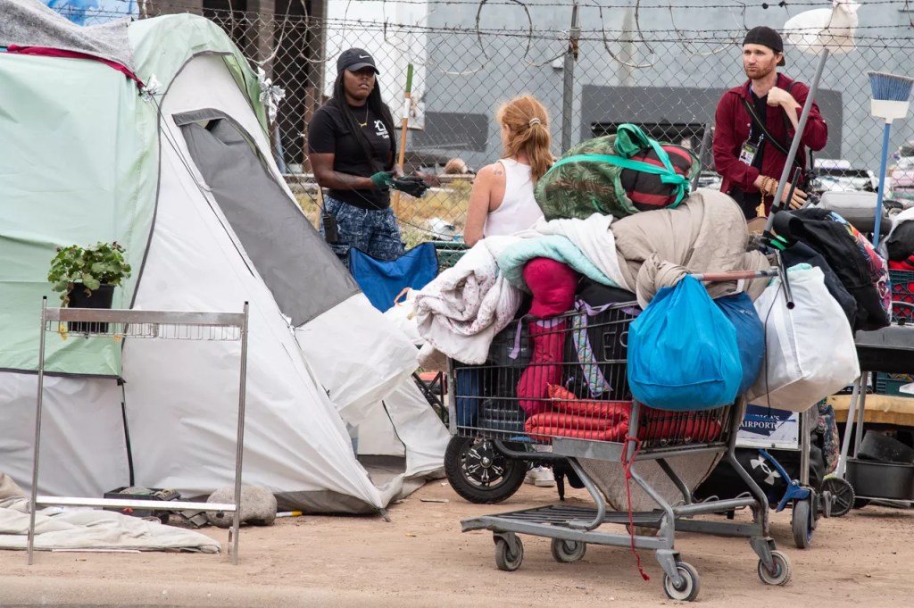 A tearful Zone resident stuffs her belongings into a shopping cart as a member of the press looks on. She was unable to take everything with her to a shelter and had to part with some possessions.