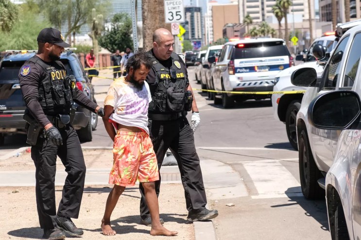 Police officers arresting an unhoused person
