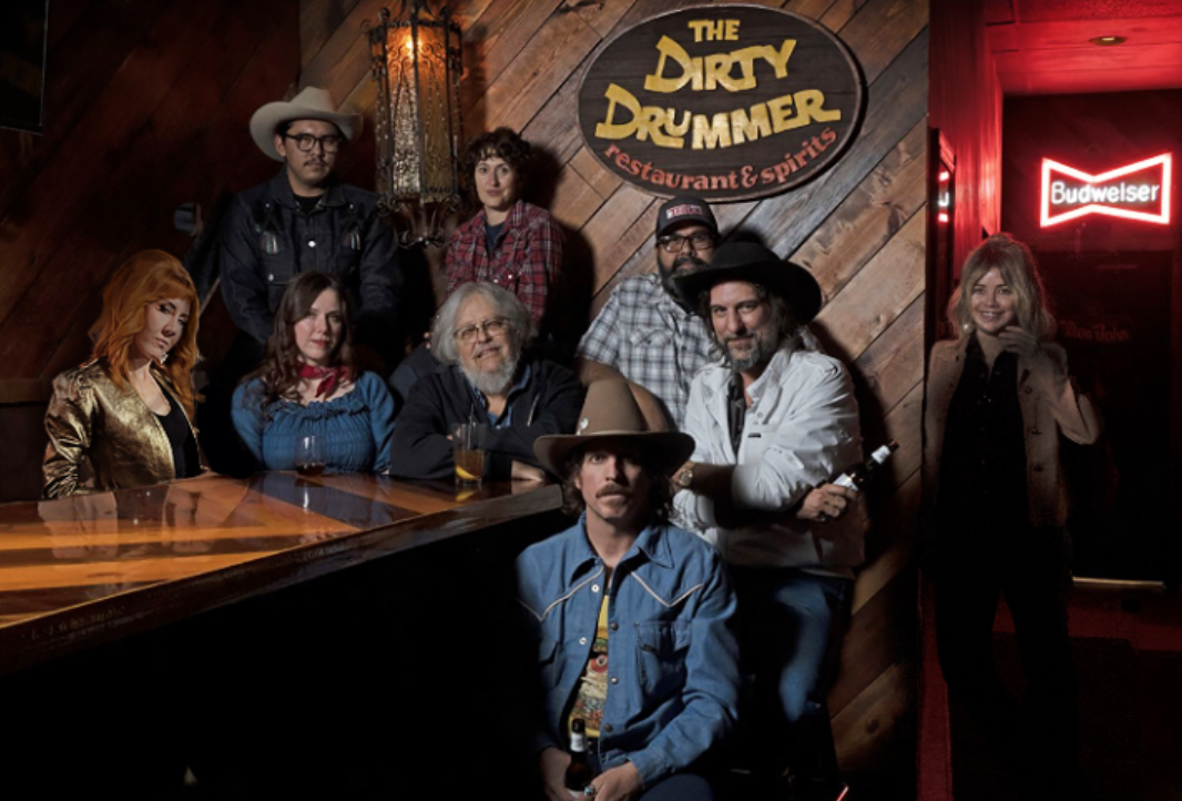 A group of men and women in Western wear sitting together in a bar.