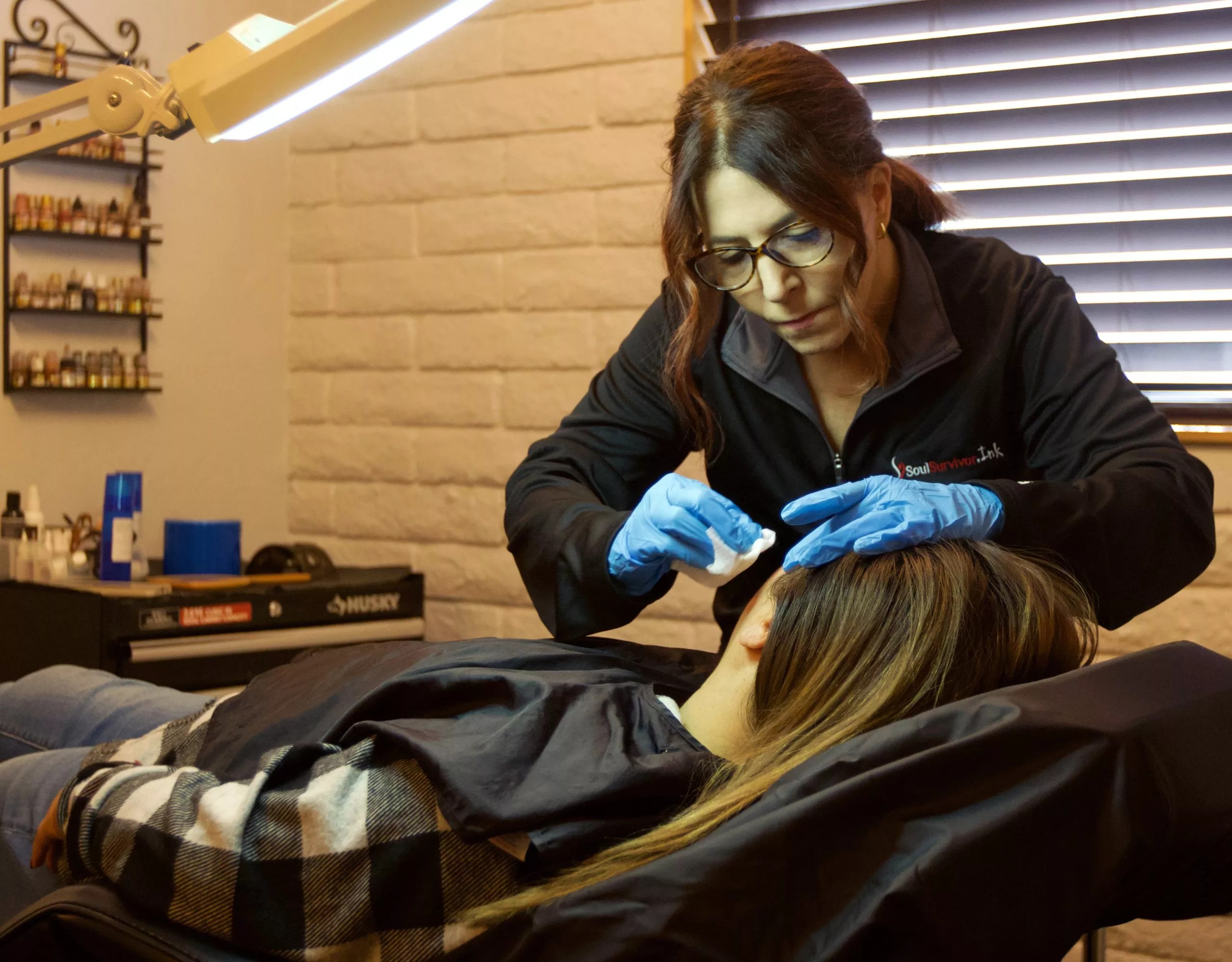 A woman removes a tattoo off of another woman.