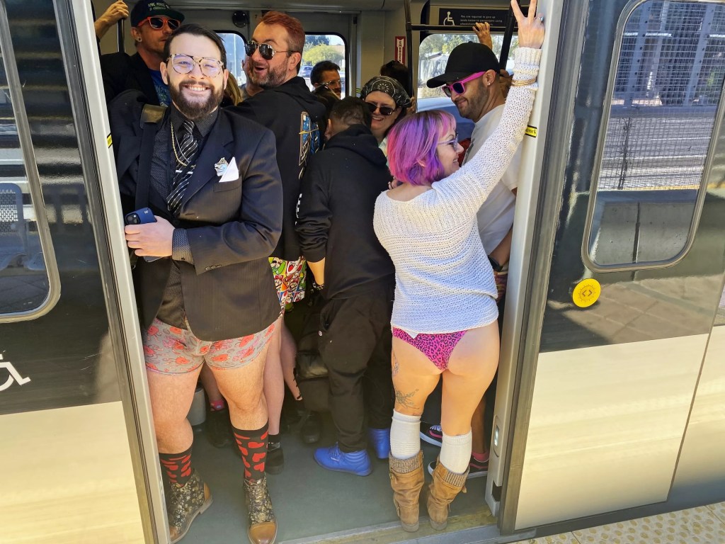 People wearing no pants on a train.