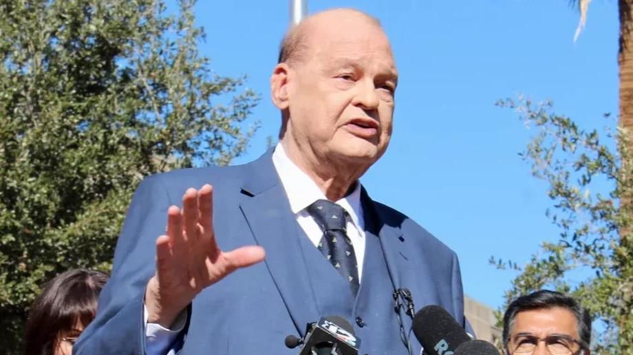 tom horne speaks at a press conference with jake hoffman standing behind him