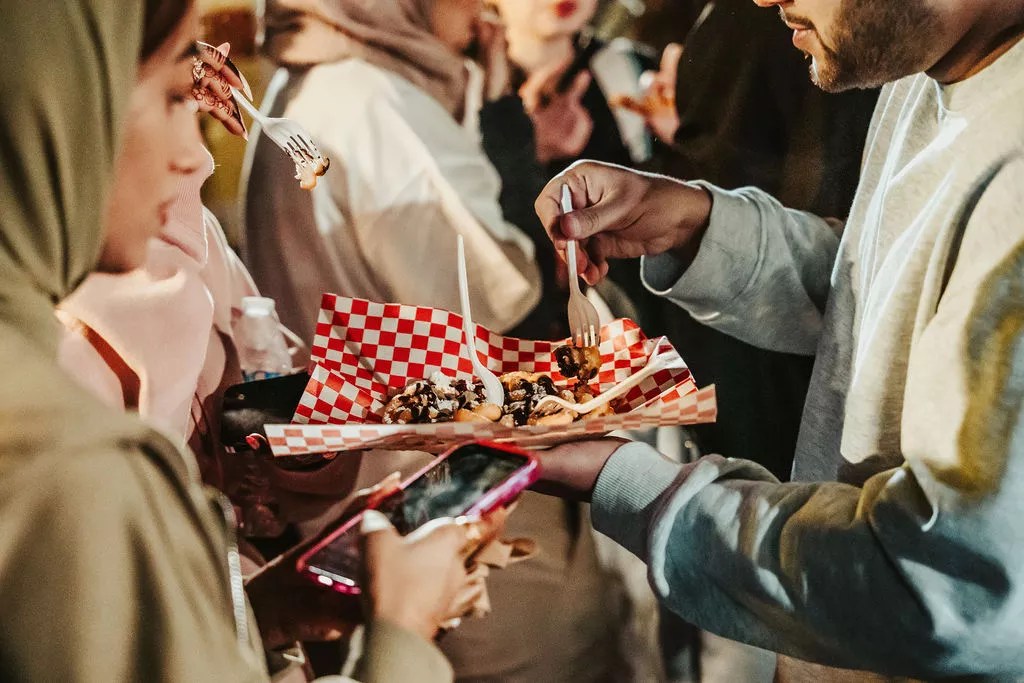 People share a plate of food at a festival.