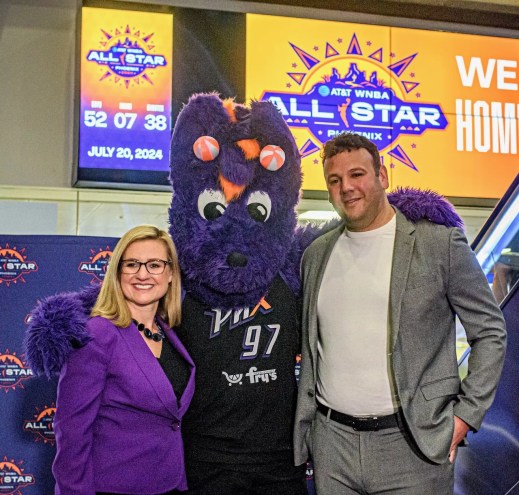 A woman and a man pose for a photo with a person in a purple dragon costume.