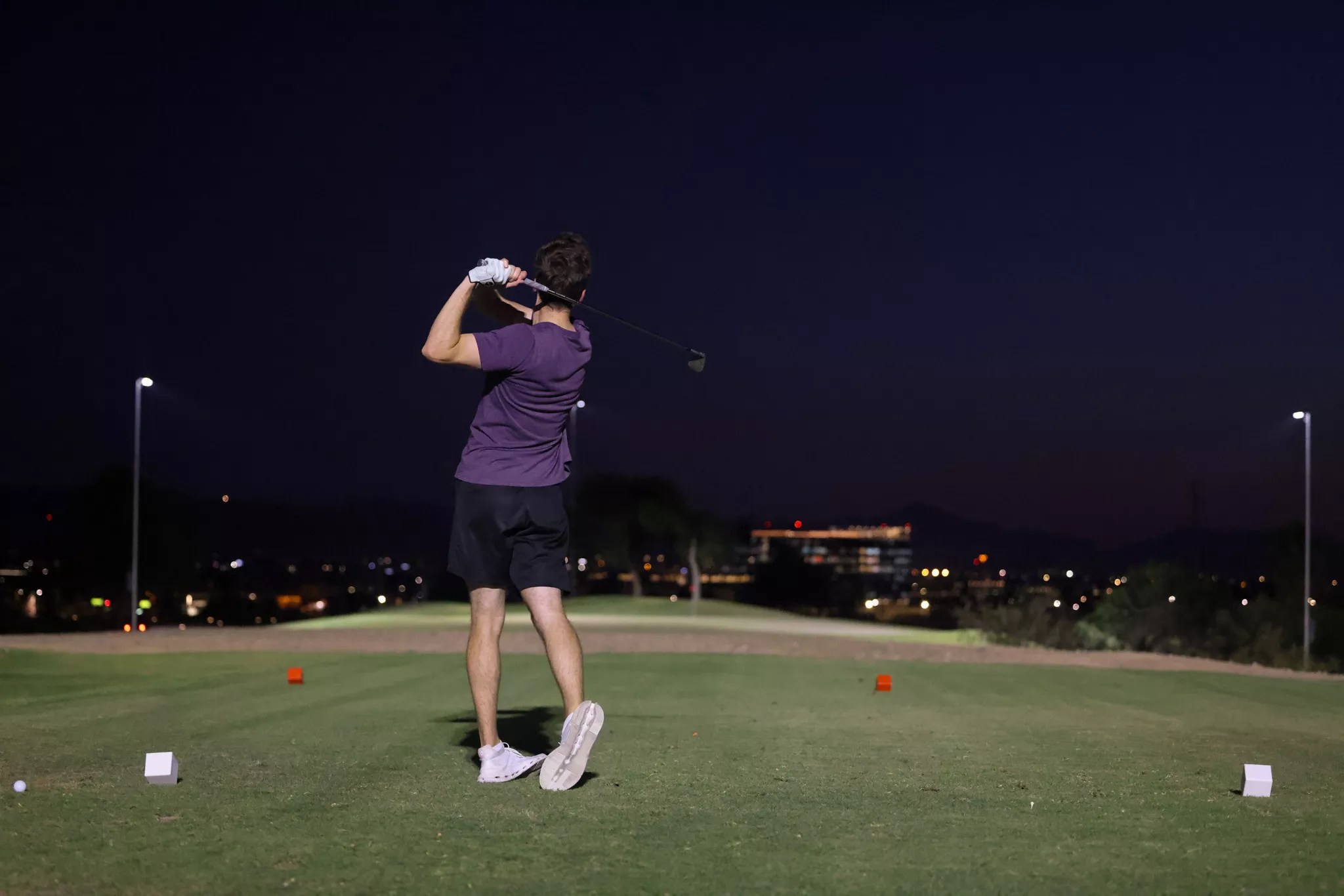 A person plays golf at night.