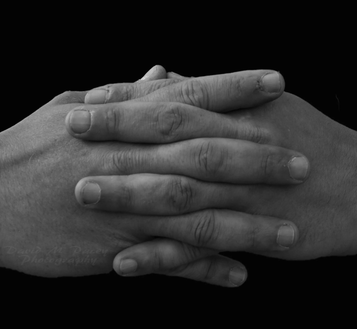 A black and white photo of folded hands.