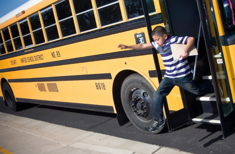 A kid jumping out of a school bus