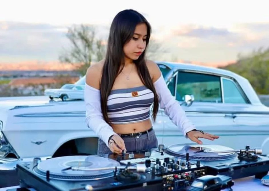 A young woman behind turntables.