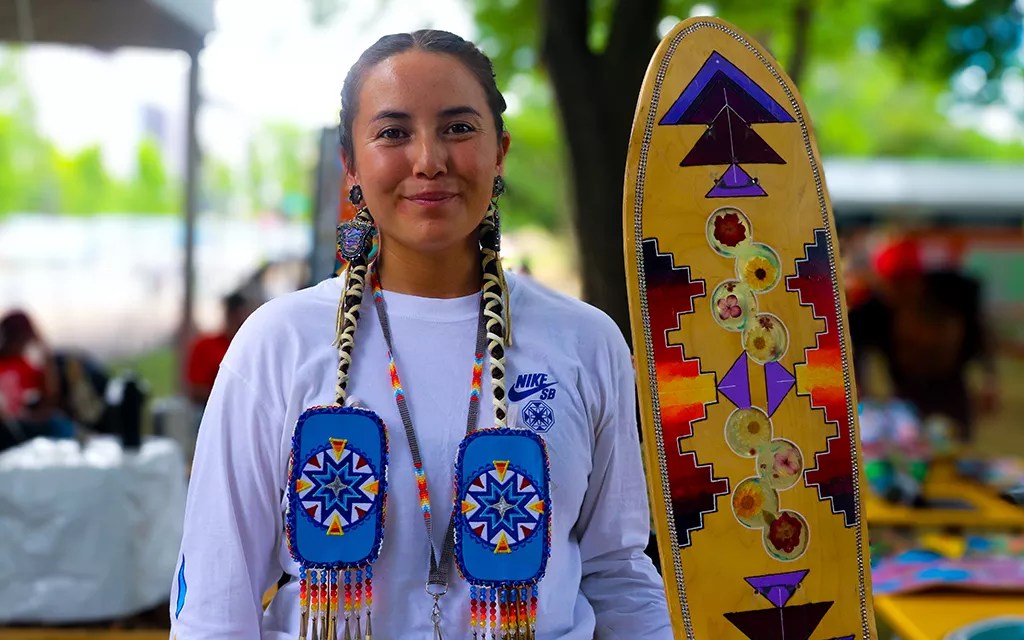 A Native woman holding a skateboard.