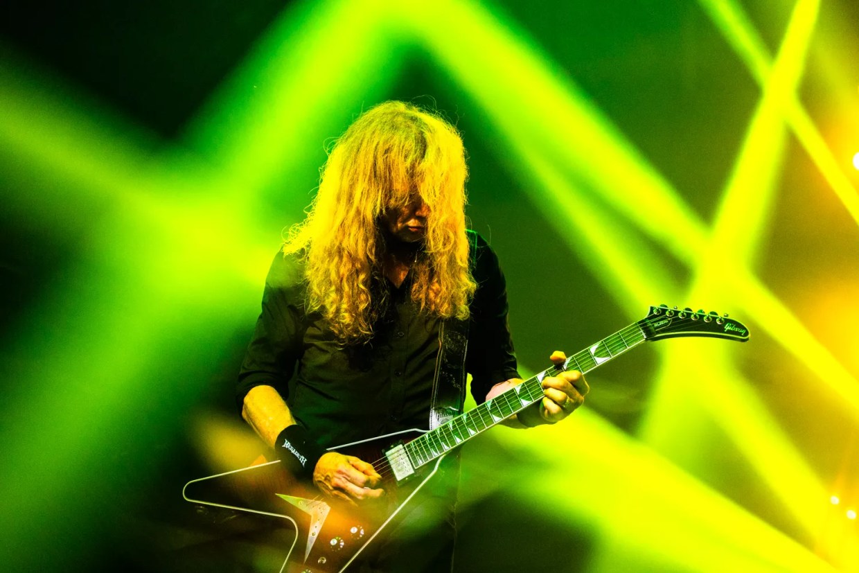 A man with long hair plays guitar.