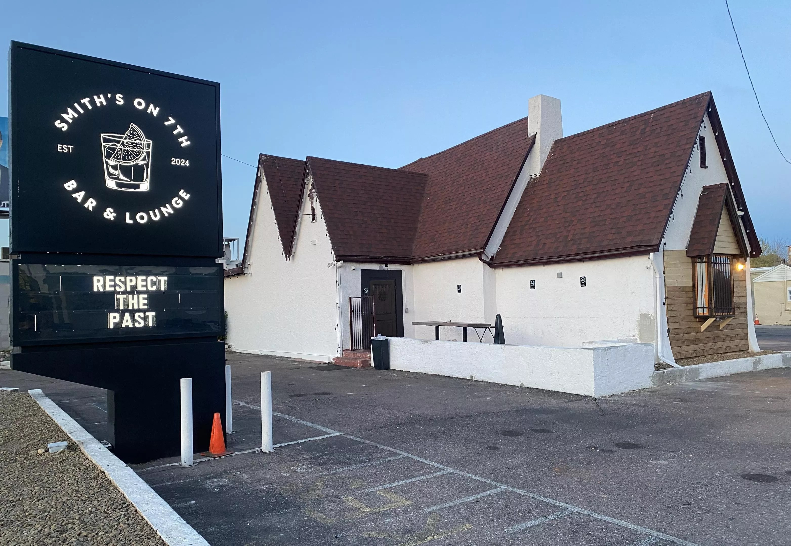 The parking lot and exterior of a former residence that has been converted into a bar.