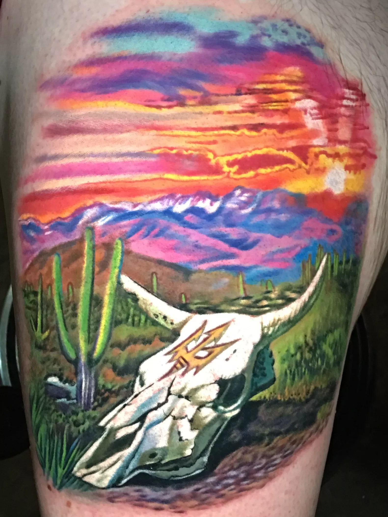A tattoo of a cow skull in the desert.