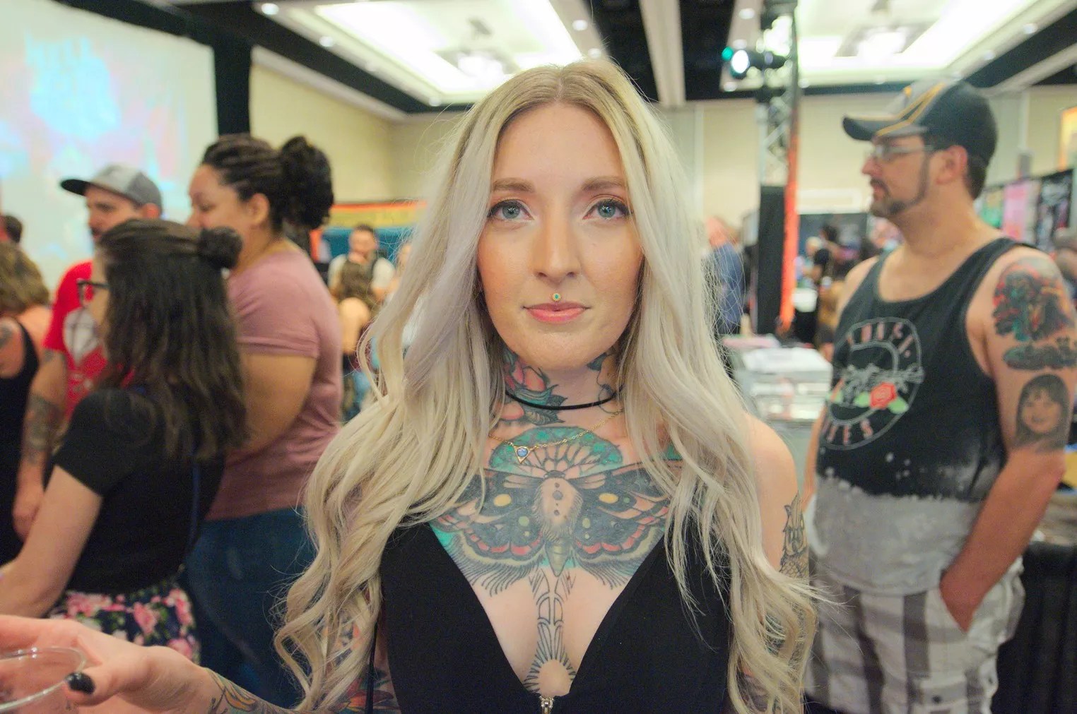 A blonde woman with a chest-piece tattoo.