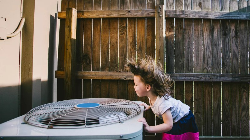 a little girl getting her hair blown back by an outdoor air conditioning unit