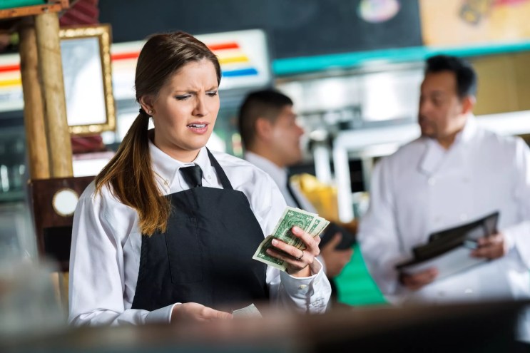 a restaurant server looks disappointedly at a meager tip