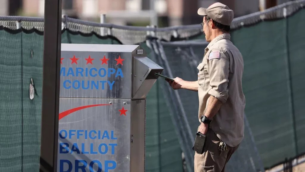 A voter drops his ballot into a drop box at the Maricopa County Tabulation and Election Center