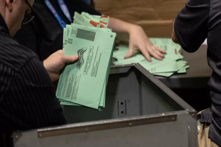 Election workers sort green envelopes of ballots at the Maricopa County Tabulation and Election Center in 2022.