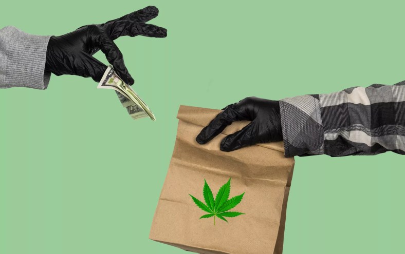 one gloved hand holds money out for another gloved hand holding a paper bag with a marjuana leaf on it