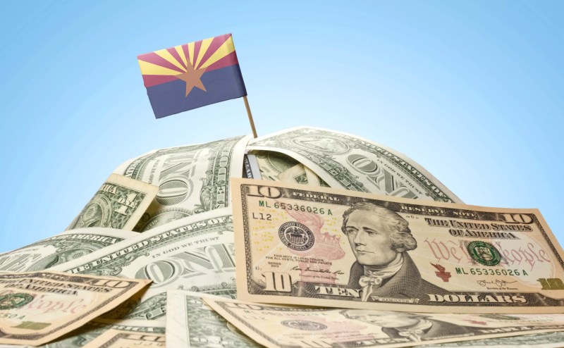 an arizona flag planted in a pile of American currency