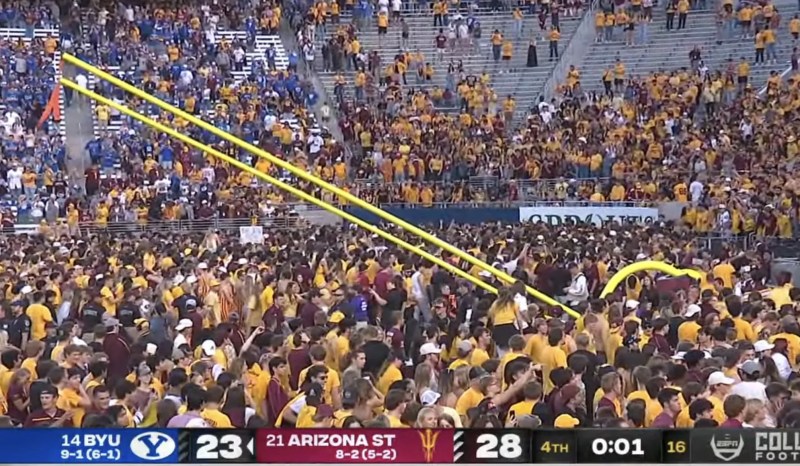a screenshot of a football game showing fans toppling the goalpost with one second still on the game clock