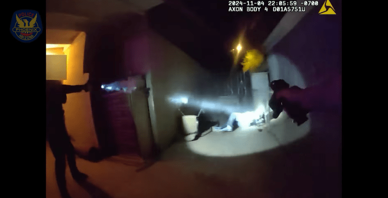 body camera footage showing arms pointing a gun at a suspect on the ground in a spotlight at night