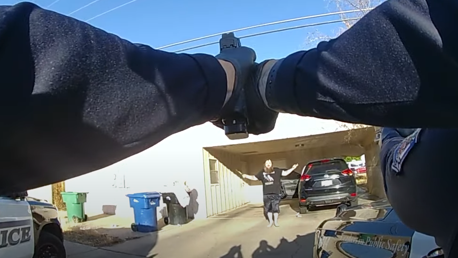 body-cam footage showing hands holding out a gun at a man who has his arms raised and a knife in one hand