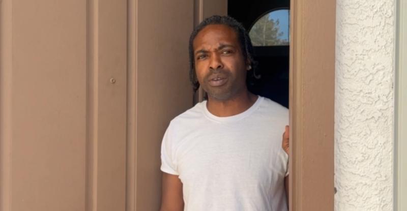 a man in a white shirt standing in an open doorway