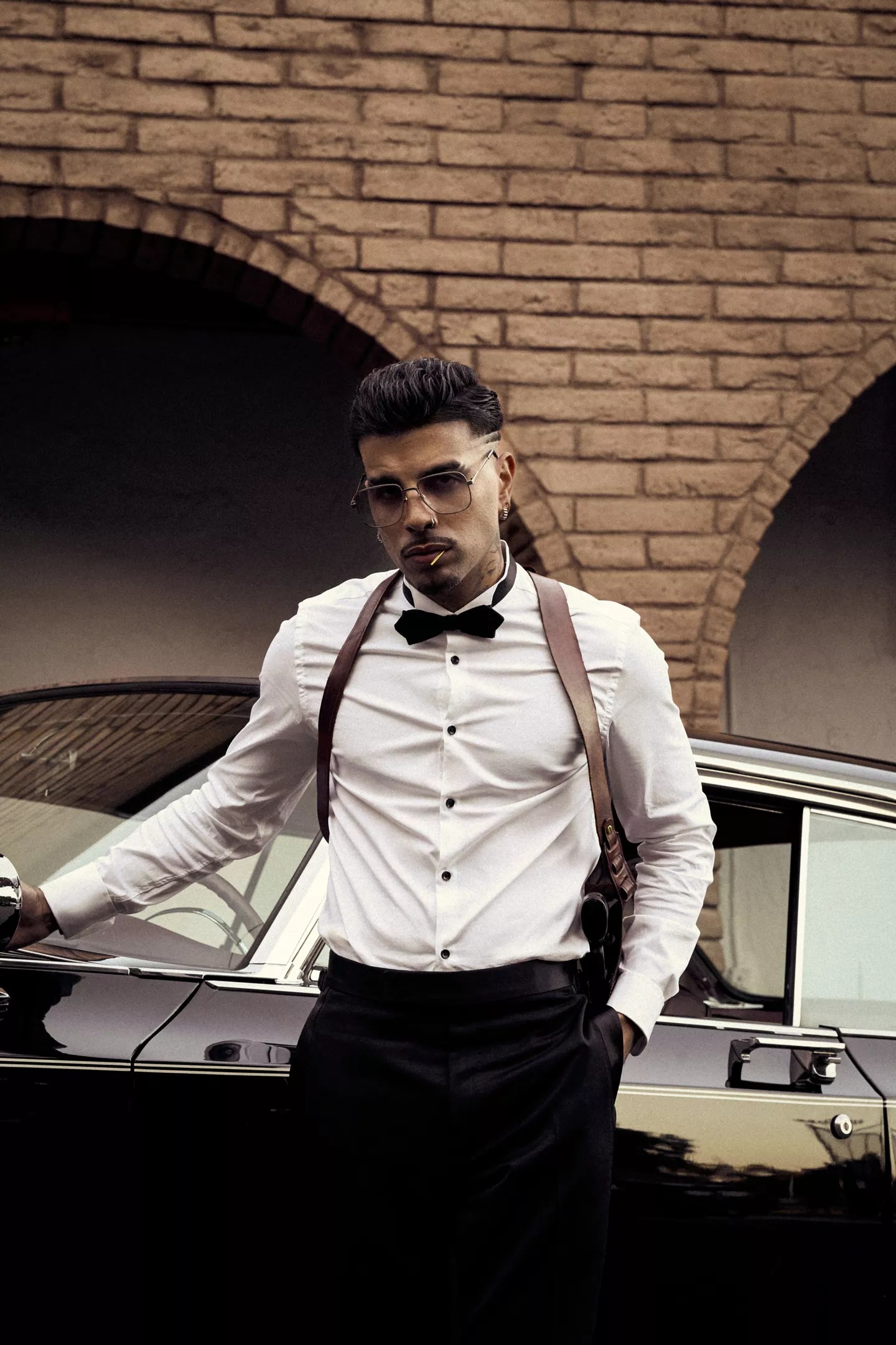 A man in formal wear standing next to a car.
