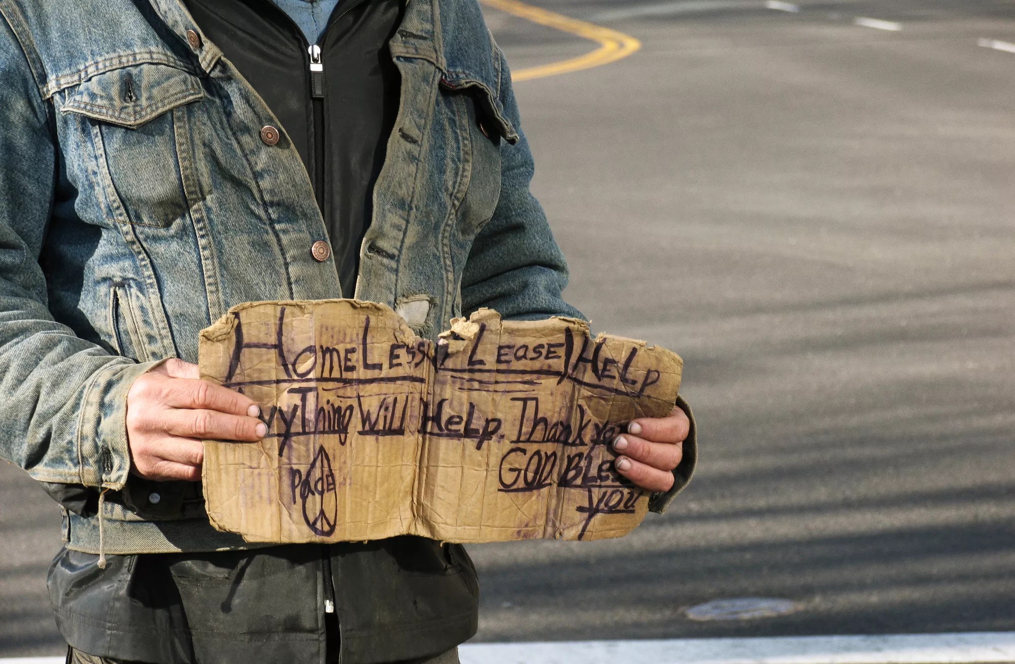 a man holding a cardboard sign near a road