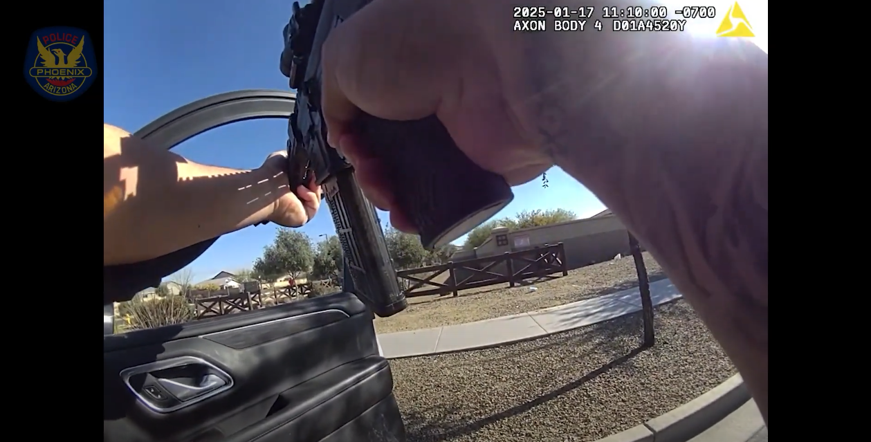body-cam footage of hands holding a rifle out an open car door
