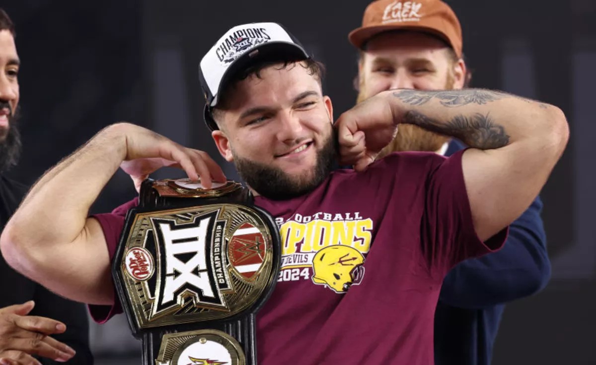cam skattebo holds a championship belt and flexes his biceps