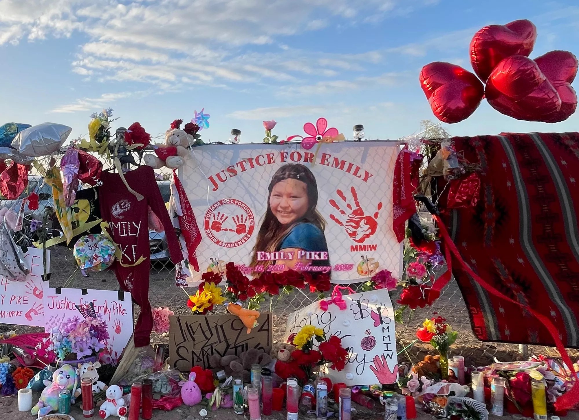 a memorial with candles and balloons and flowers and a picture of a teenage Native American girl