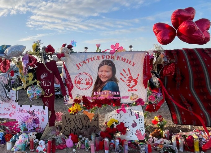 a memorial with candles and balloons and flowers and a picture of a teenage Native American girl