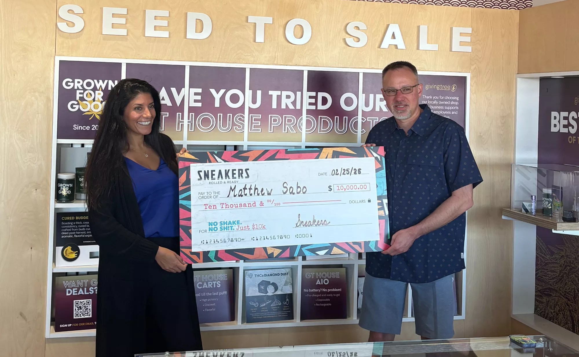 a woman hands a big $10,000 check to a man