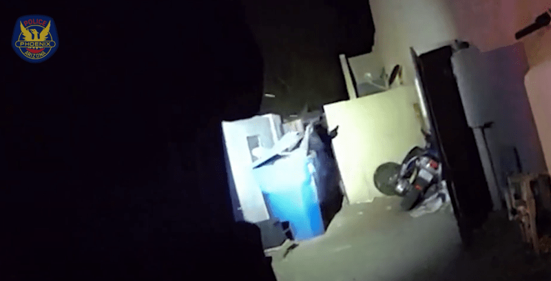 body-cam footage at night of a hand holding something popping out of a blue recycling bin