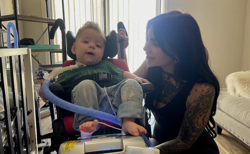 a woman smiles at a small child in a medical chair