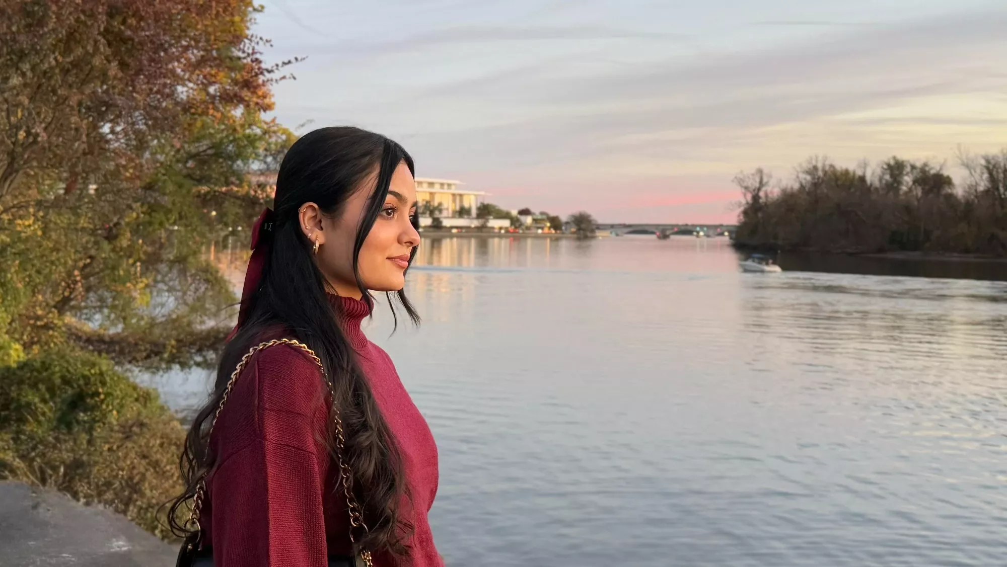 a woman stares into the distance near a body of water