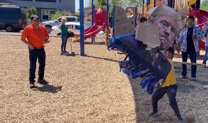 a kid in spider-man face paint bashes a donald trump pinata