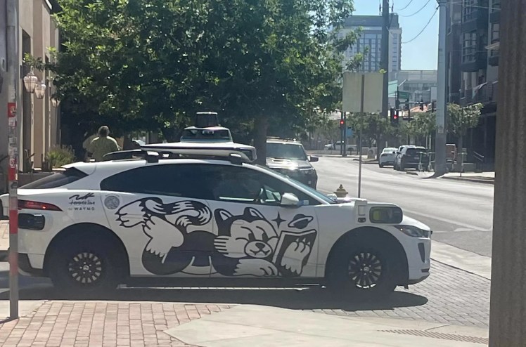 a waymo driverless car with a cartoon cat on the side