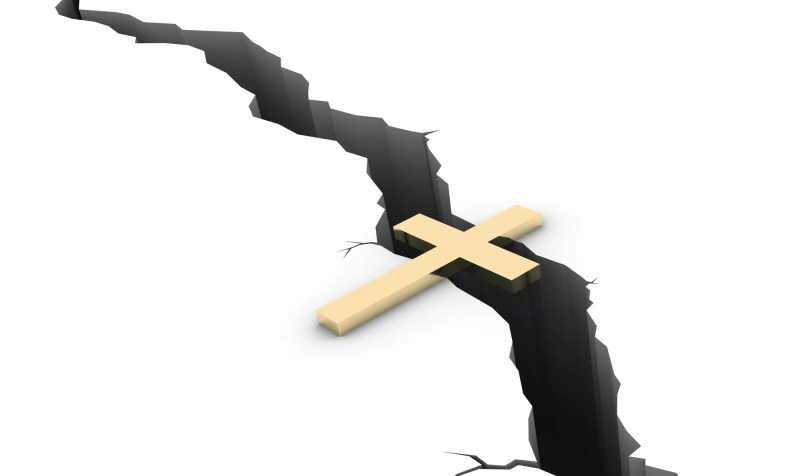 a cross spans a crack in the ground