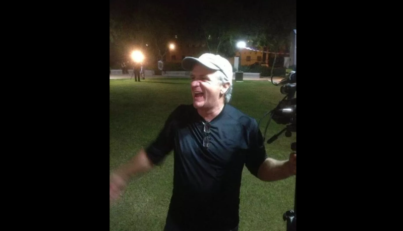 a man smiles at night holding a video camera