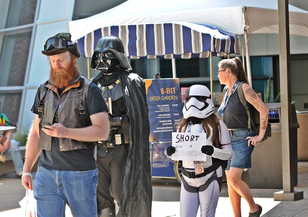 Phoenix Fan Fusion attendees outside the Phoenix Convention Center, including an adult dressed as Darth Vader and a child in a stormtrooper costume.