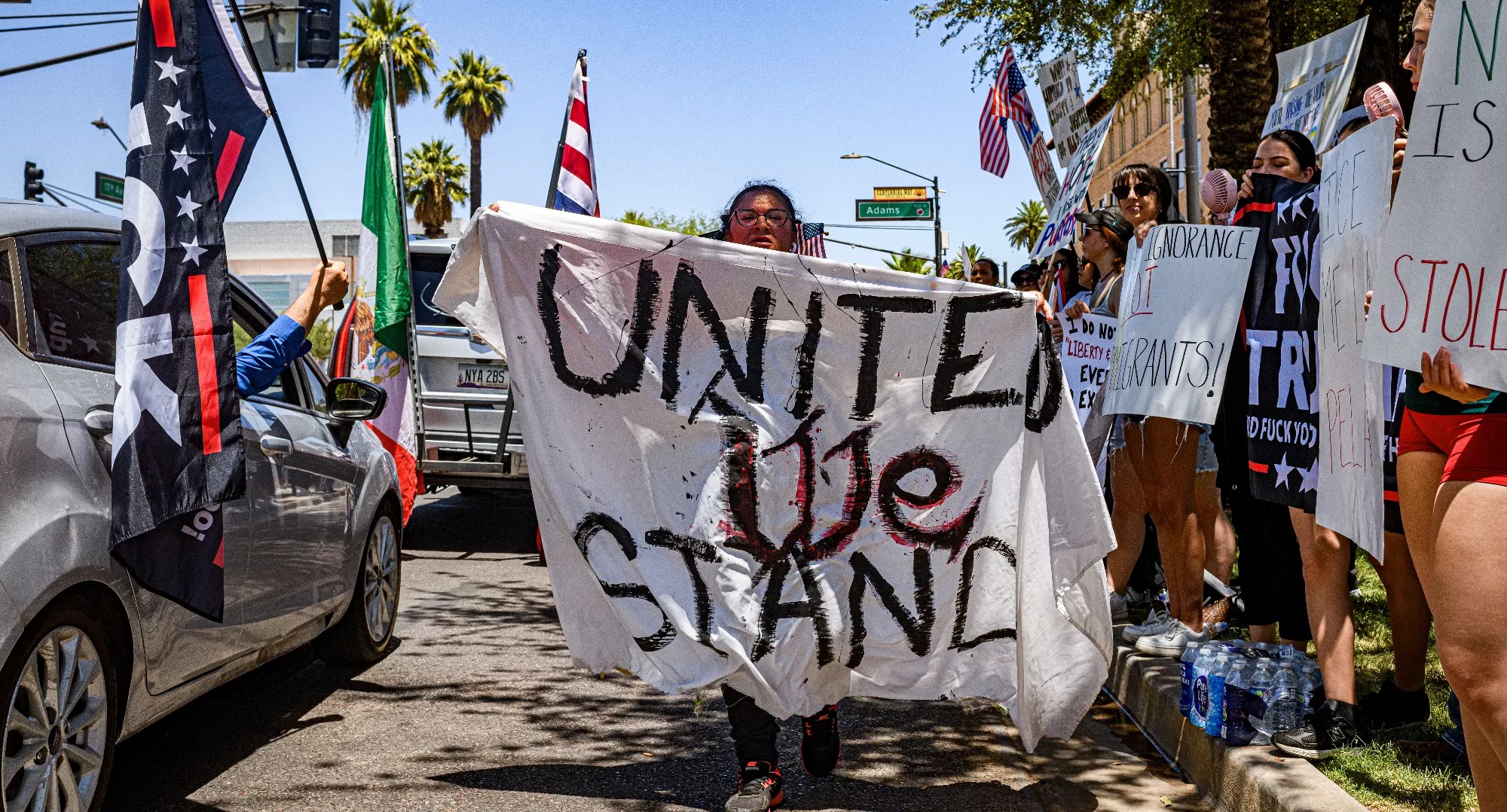 a woman walks down the street holding a banner that says "united we stand"